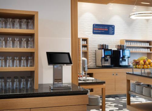 a coffee shop with a counter with a tv on it at Holiday Inn Express Munich City West by IHG in Munich