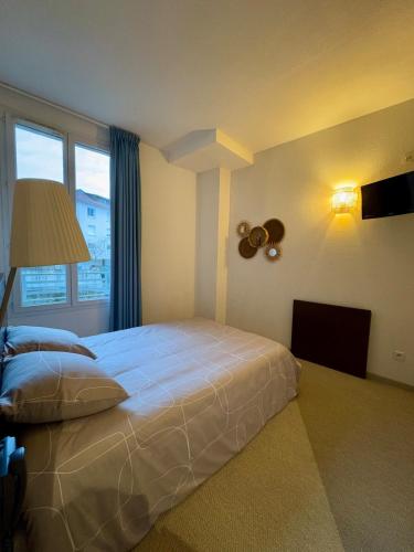 une chambre avec un grand lit blanc et une fenêtre dans l'établissement Studio Cosy à Deux Pas du Sanctuaire, à Lourdes