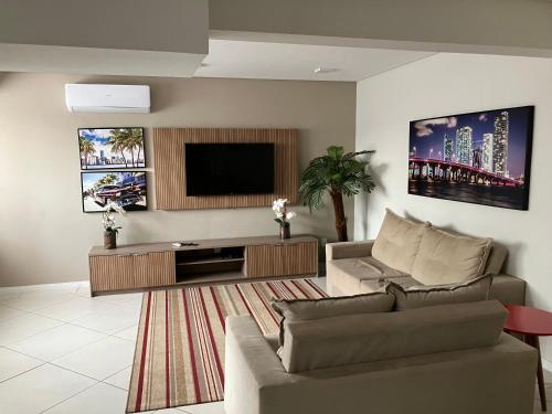 a living room with a couch and a flat screen tv at Spot Miami in Araraquara