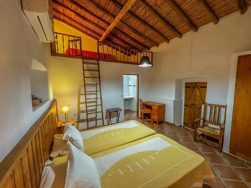 a large room with a bed and a ladder at Casas do Palheiro Velho in Castro Marim