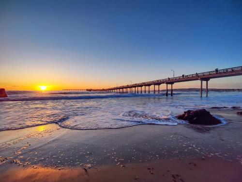 a pier on the beach at sunset with the ocean at Modern Newly Renovated 2BR Apt in Heart of Ocean Beach in San Diego