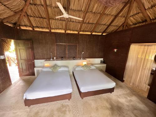 two beds in a room with a ceiling at Isla Única- Islas del Rosario in Isla Grande