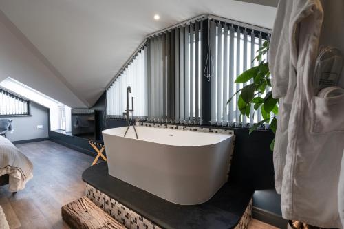 a bathroom with a large white bath tub next to a window at Uno Carbis Bay - Boutique Luxury Accommodation in Carbis Bay