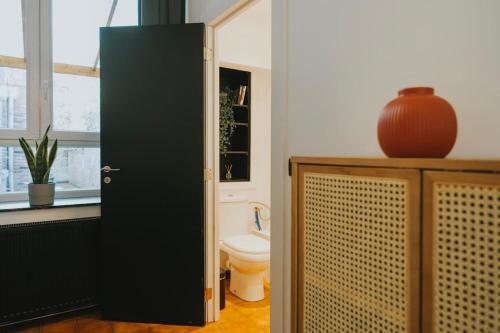 a bathroom with a toilet and a black door at 2 bedroom apartment near the city center in Liège