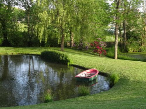 un petit bateau rouge au milieu d'une rivière dans l'établissement Gites au Chateau de Vernieres, à Talizat