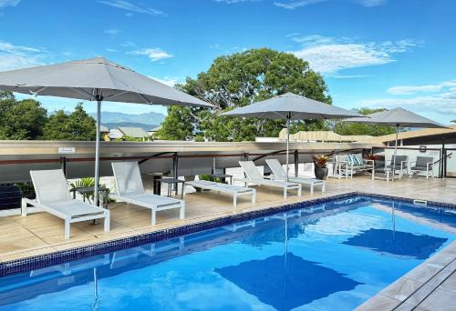 a swimming pool with chairs and umbrellas on a building at Reef Luxury Apartment in Port Douglas