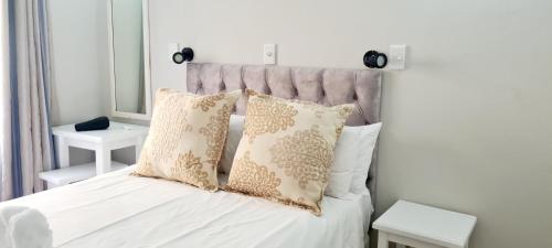 a white bed with two pillows on top of it at Chakas Rock Beach Chalet 32 in Ballito