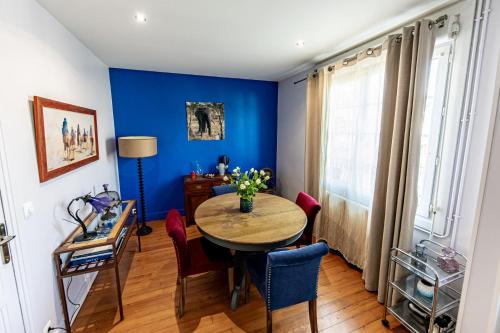 une salle à manger avec des murs bleus et une table et des chaises dans l'établissement Maison de ville vue port, à Saint-Valery-en-Caux