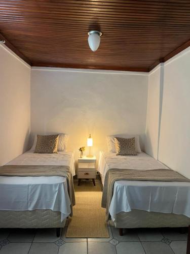 a room with two beds and a lamp on a table at Cantinho dos Berens in Diamantina