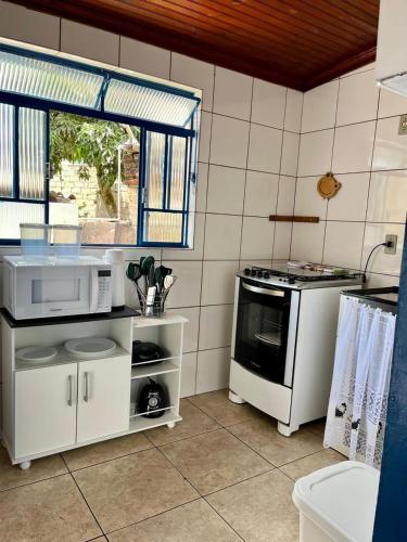 a kitchen with a microwave and a stove at Cantinho dos Berens in Diamantina