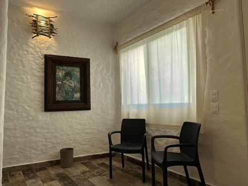 a dining room with two chairs and a table and a window at Habitacion Cerca del centro 1 in Tepoztlán