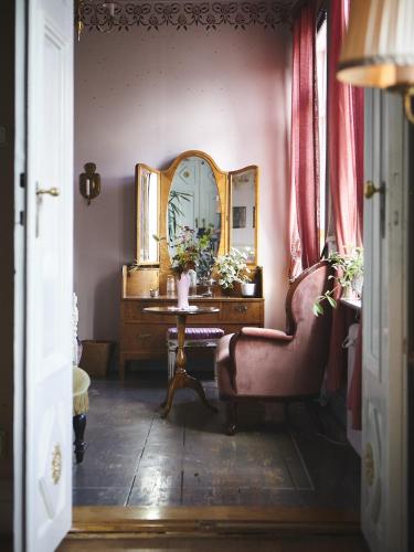a room with a mirror and a chair and a desk at Osaby Säteri in Tävelsås