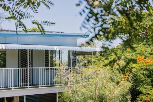 a building with a balcony with trees in the foreground at Sharon - Pet Friendly Beach Cottage in Town - Holiday Yamba in Yamba