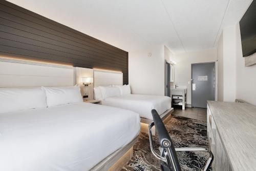 a hotel room with two beds and a desk at Oakfield Hotel & Suites, an Ascend Collection Hotel in Rochester