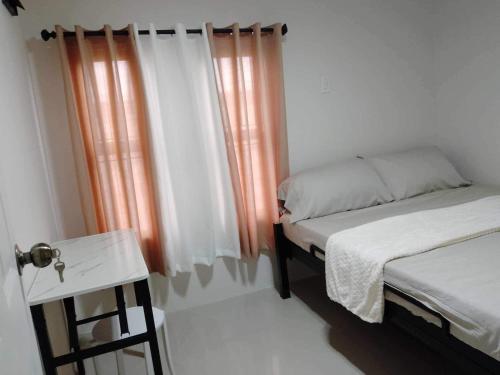 a small bedroom with two beds and a table at Casa de Ligaya San Pablo in San Pablo