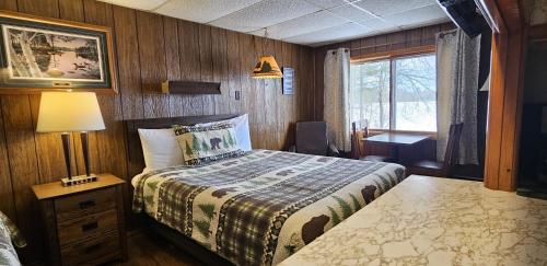 a bedroom with a bed and a lamp and a window at Lakeshore Motel Ice Lake in Iron River