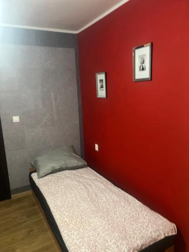 a bed in a room with a red wall at Kwatery pracownicze Rumia in Rumia
