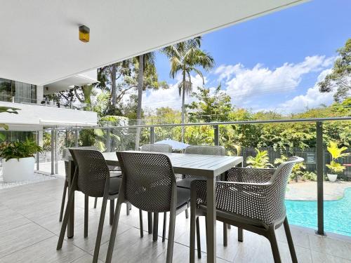 a dining room with a table and chairs and a pool at Chic 2 bdrm Poolside Apartment in Noosa Heads