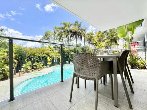 an open balcony with a table and chairs and a swimming pool at Chic 2 bdrm Poolside Apartment in Noosa Heads