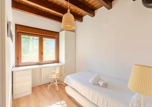 a bedroom with a bed and a desk and a window at Casa Rural Orós in Orós Alto