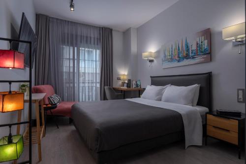 a hotel room with a large bed and a chair at Galleries Elegant Suites in Thessaloniki