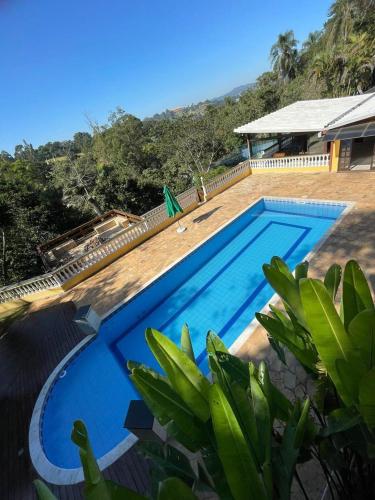 a large blue swimming pool next to a house at Sítio Mairiporã-Piscina Aquecida in Mairiporã
