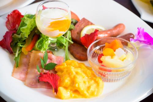 a white plate of food with a drink and vegetables at Scallop Beach Condominium in Onna