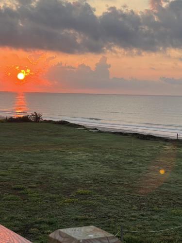 a sunset on the beach with the ocean and the sun at Jolly Roger - Themed Beachfront 5BR with Arcade in Gilchrist