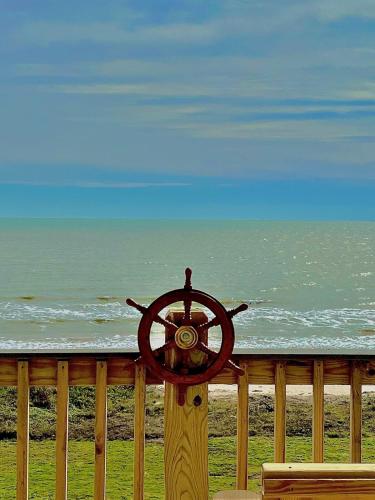a wooden pole with a steering wheel on the beach at Jolly Roger - Themed Beachfront 5BR with Arcade in Gilchrist