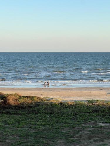 a beach with people walking in the water at Jolly Roger - Themed Beachfront 5BR with Arcade in Gilchrist