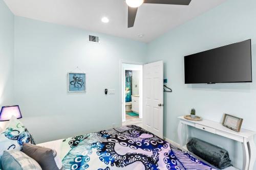 a bedroom with a bed and a flat screen tv at Jolly Roger - Themed Beachfront 5BR with Arcade in Gilchrist