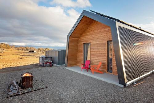 a cabin with a red chair next to a fire at Avonside Alpine Estate - Jindabyne in Coolamatong