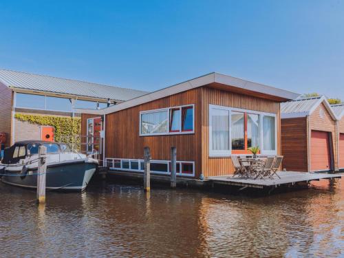 a house on a dock with a boat in the water at Woonark De Woude in Uitgeest