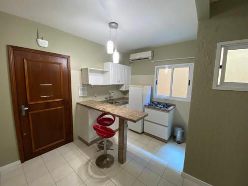 a small kitchen with a counter and a red stool at Hotel Morada Del Este in Canoas
