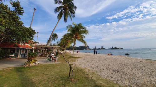 a beach with palm trees and people on it at Seaview Regency Tanjung Tuan Apartment A7-4 in Pulau Burung