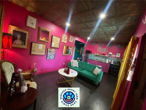 a living room with a green couch and pink walls at Boho Nights in Sanford