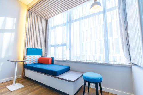 a chair and stool in a room with a window at Holiday Inn Express Harbin Qunli by IHG in Harbin