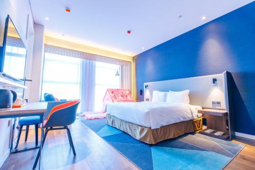 a hotel room with a bed and a desk and a table at Holiday Inn Express Harbin Qunli by IHG in Harbin