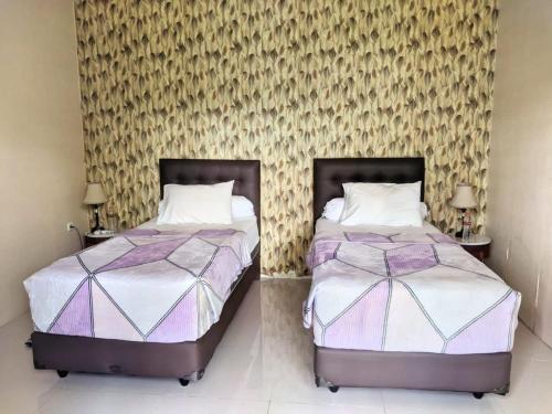two beds sitting next to each other in a bedroom at Amuya Home Stay in Waingapu