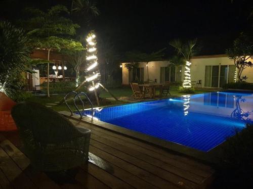 a swimming pool at night with a christmas tree next to it at Amuya Home Stay in Waingapu