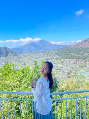a woman standing on a balcony overlooking a valley at Pinggan Campside Glamping in Baturaja