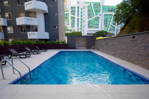 Una piscina con sillas y edificios al fondo. en Conjunto Residencial Ambar Reserva, en Armenia