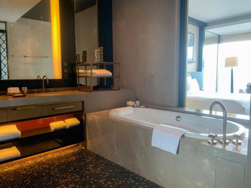 a bathroom with a bath tub and a bed at Rosewood Phnom Penh in Phnom Penh