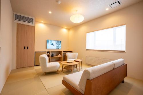 a living room with a couch and chairs and a window at Tanuki Nozawa in Nozawa Onsen