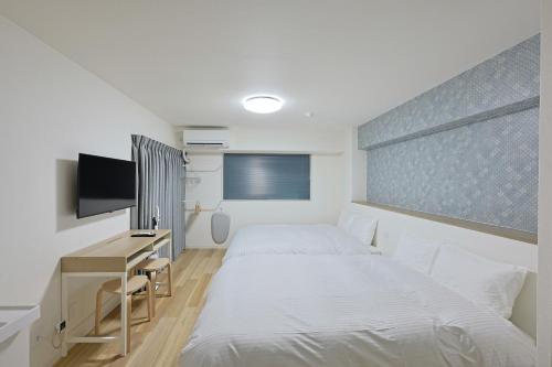 a bedroom with a bed and a desk and a tv at グランシャーギ in Osaka
