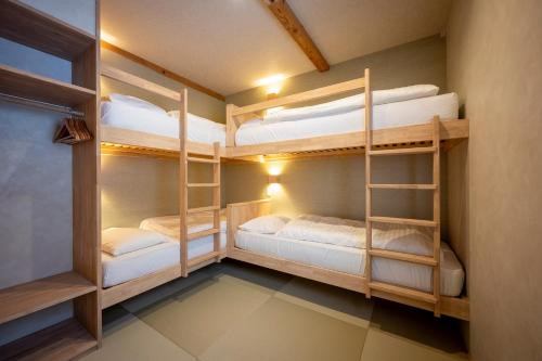 a room with two bunk beds in it at Tanuki Nozawa in Nozawa Onsen