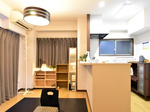 a kitchen and living room with a counter and a chair at Alphabed広島平和大通り in Hiroshima