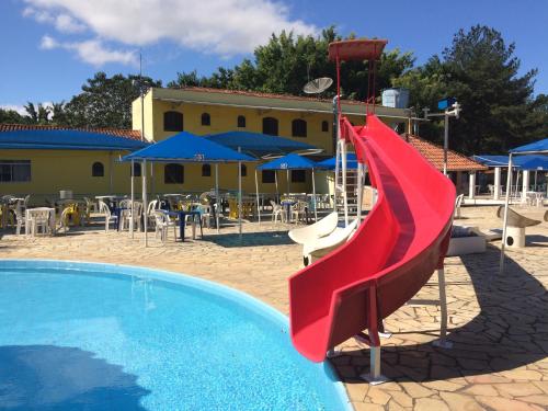 a red slide in front of a swimming pool at Hotel Fazenda Pé da Serra in Bom Sucesso