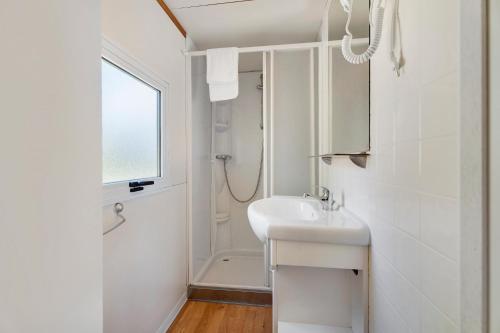 a white bathroom with a sink and a shower at Camping Royal in Pettenasco