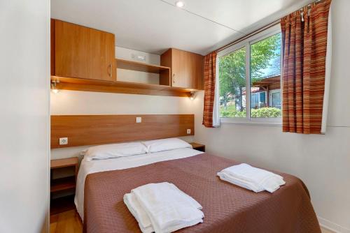 a bedroom with a bed with two towels on it at Camping Royal in Pettenasco